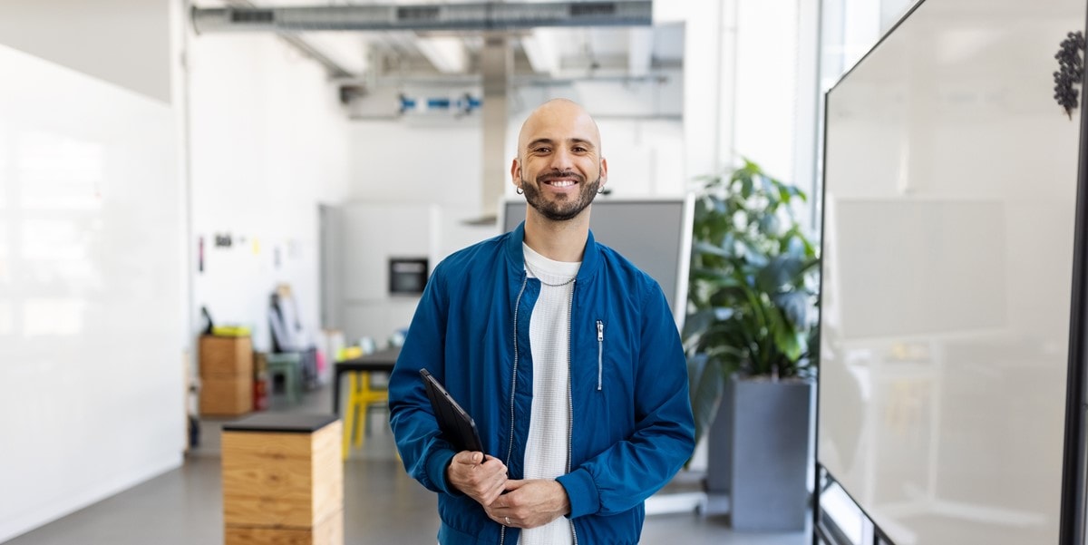 man in office, smiling, holding laptop