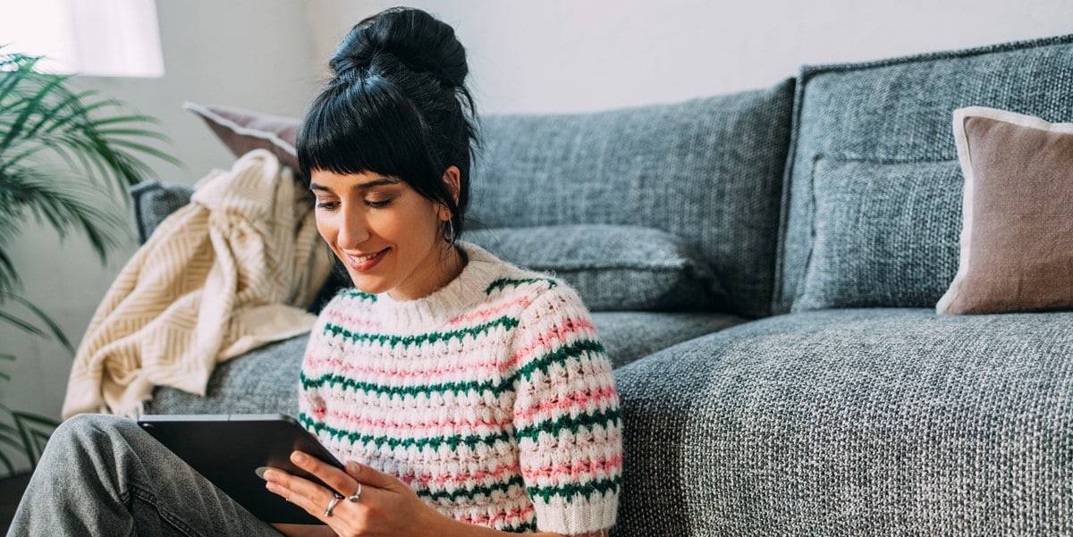 woman reading tablet sitting by couch