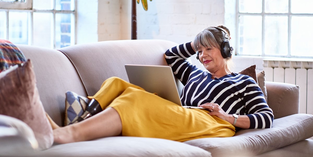 woman working from home on couch, using laptop